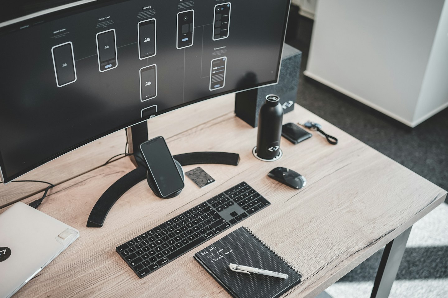 Escritorio moderno de diseñador con monitor mostrando wireframes de aplicaciones.